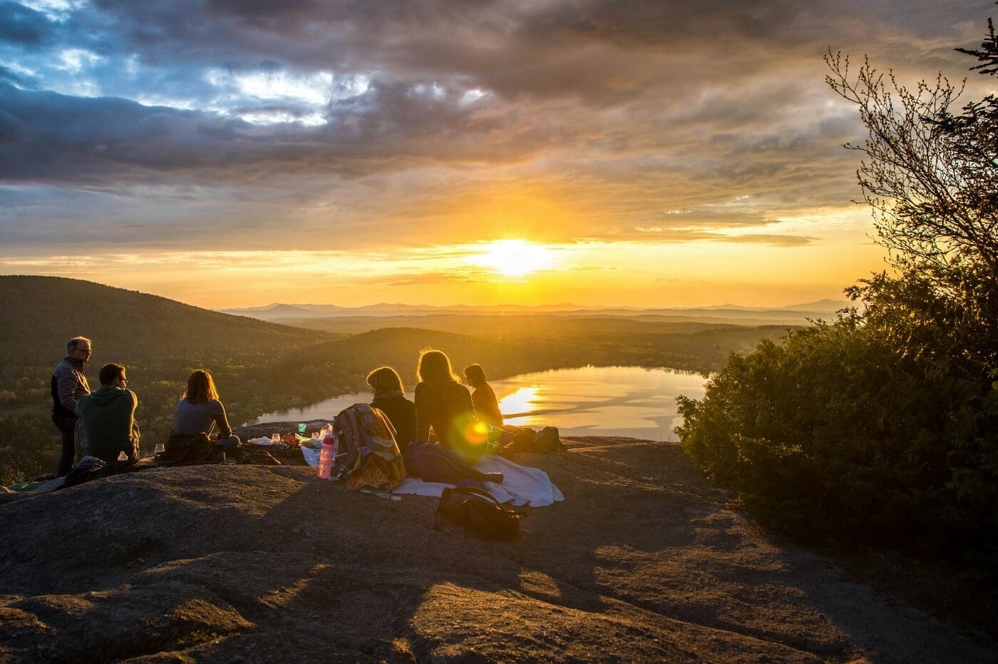 Diverse group of friends watching a sunset over a serene lake, symbolizing global connection and shared future.