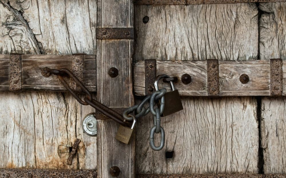 Old, chained, and padlocked wooden door, symbolizing restricted access and stifled entrepreneurship in Japan due to tough visa requirements.