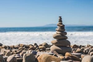 Zen rock cairn on a beach with ocean waves, symbolizing work-life balance and modern productivity.